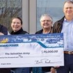 Six people standing in a row, looking at the camera and two of them are holding a large check made out to the Salvation Army from Idaho Power.