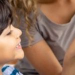Child helping mother adjust a smart thermostat.